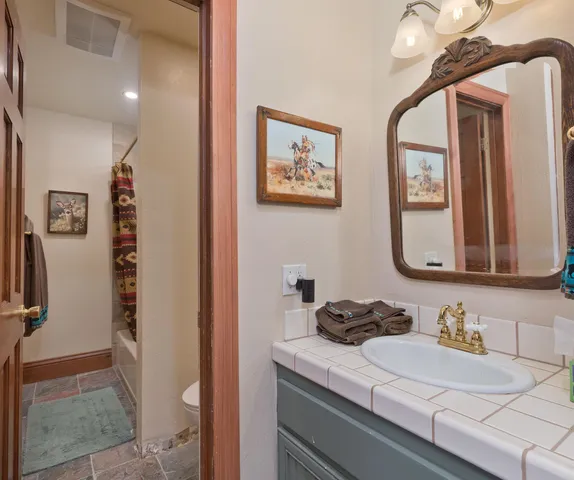 a bathroom with a granite countertop sink mirror vanity and a toilet