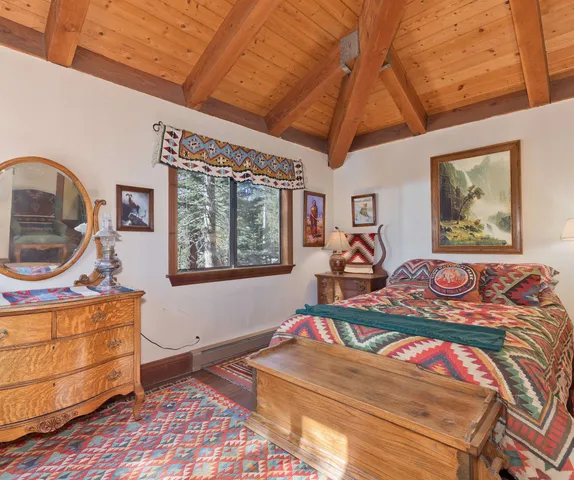 a bedroom with a bed and dresser with wooden floor