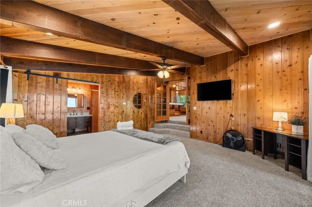 a large bedroom with a bed and a flat tv screen on wall