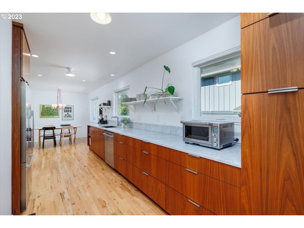 7519 Southwest 53rd Avenue Portland, OR 97219 - Photo 11 of 30 a kitchen with stainless steel appliances granite countertop wooden cabinets a dining table and chairs