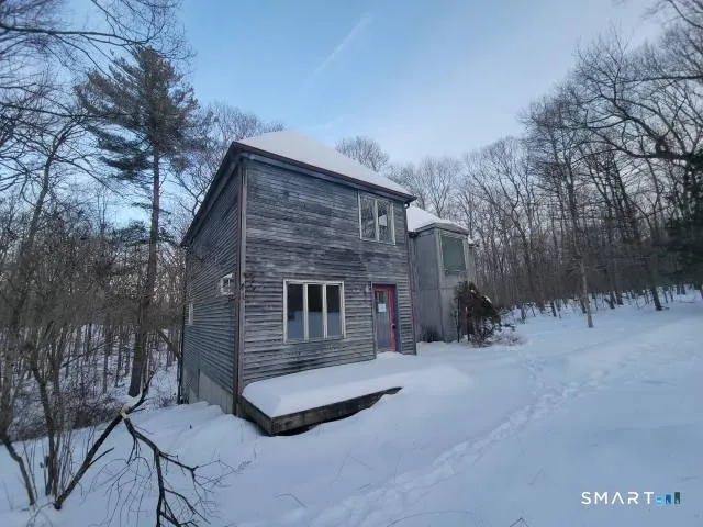 a backyard of a house with large trees and outdoor seating