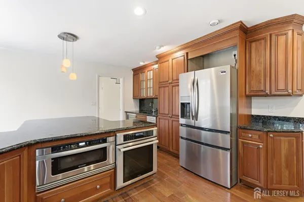 a kitchen with granite countertop a refrigerator stove and microwave