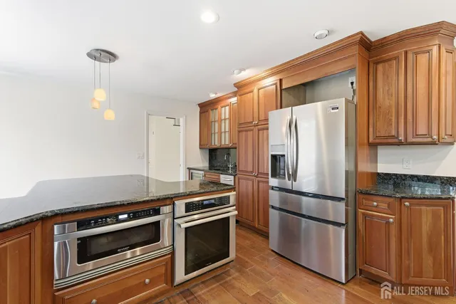 a kitchen with granite countertop a refrigerator stove and microwave