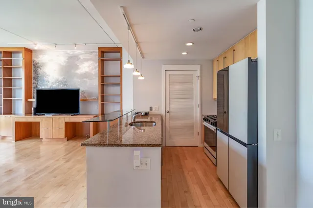 a living room with stainless steel appliances furniture and a flat screen tv