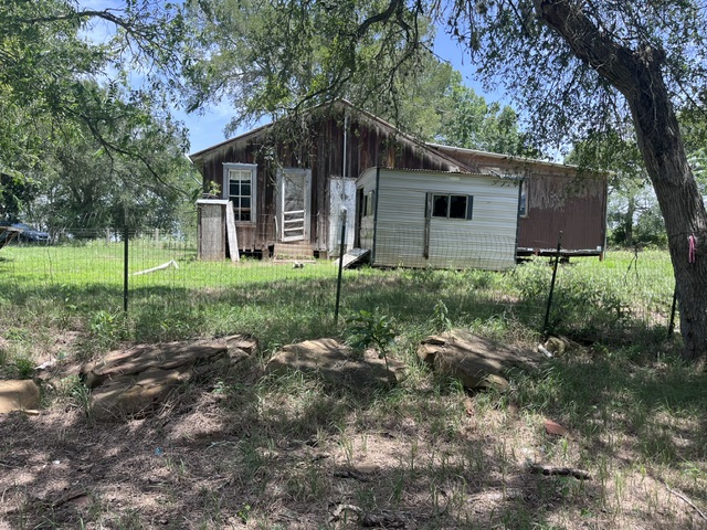 344-343 Bateman Road Red Rock, TX 78662 - Photo 8 of 15 Back of the house, fencing, large stones, and shaded area.