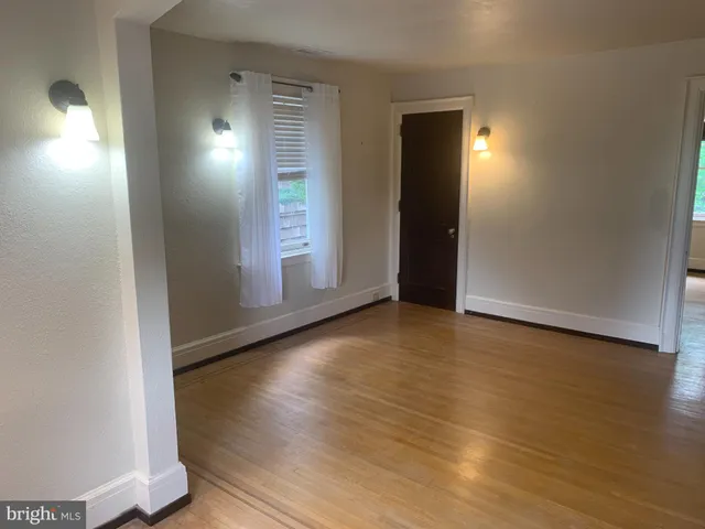a view of a hallway with wooden floor and a living room