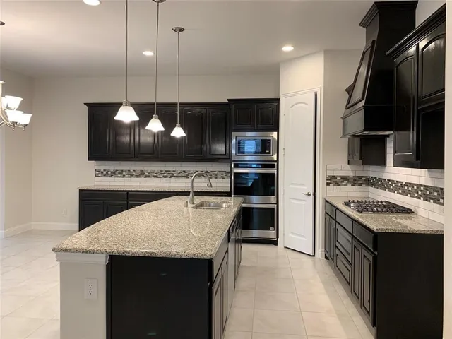 a kitchen with stainless steel appliances granite countertop a sink a stove and a wooden floors