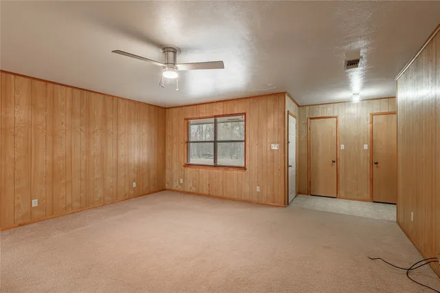 an empty room with a chandelier fan and windows