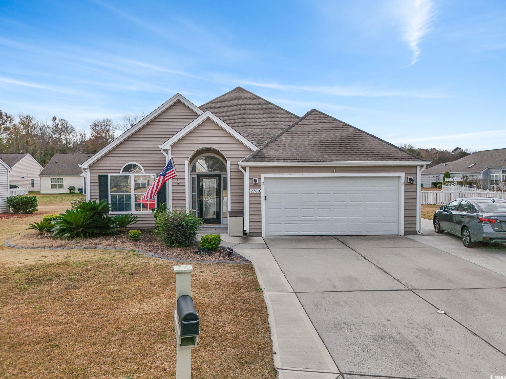 View of front of property with concrete driveway, a front yard, roof with shingles, and an attached garage