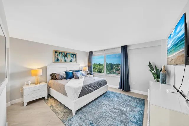a bedroom with a large bed and a potted plant on a dresser