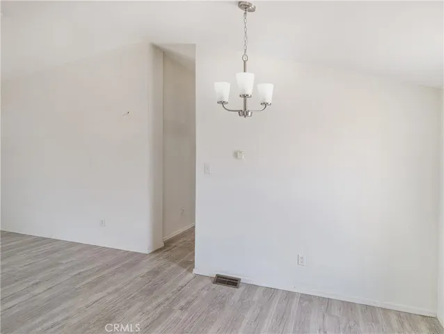 a view of empty room with wooden floor and chandelier