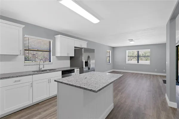 a kitchen with granite countertop a sink and dishwasher a wooden floor with white walls