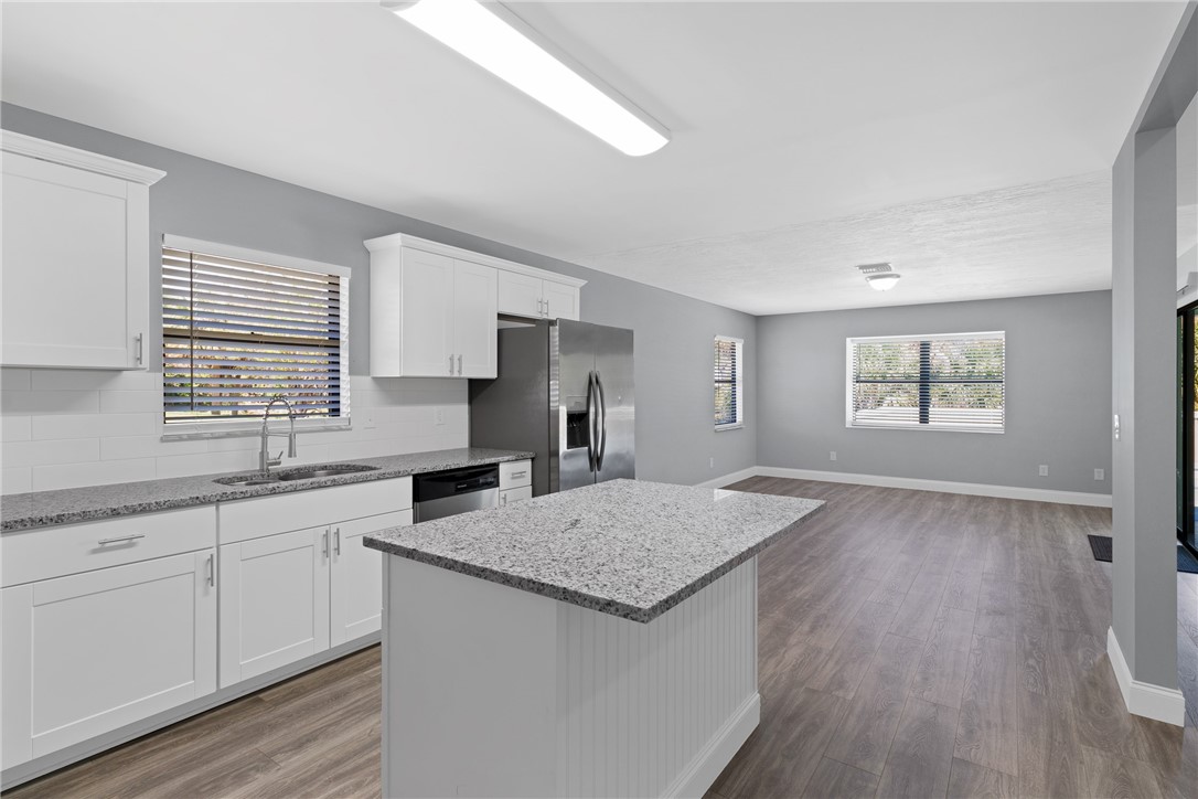 462 Watercrest Street Sebastian, FL 32958 - Photo 12 of 36 a kitchen with granite countertop a sink and dishwasher a wooden floor with white walls