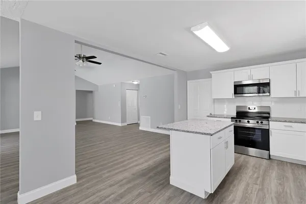 a kitchen with stainless steel appliances granite countertop a stove top oven a sink dishwasher and a refrigerator with wooden floor