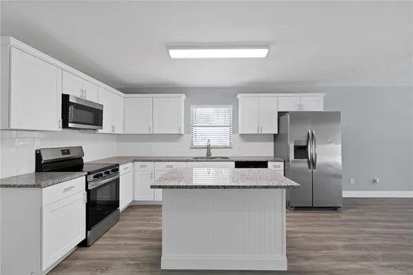 a kitchen with granite countertop a refrigerator stove top oven and sink