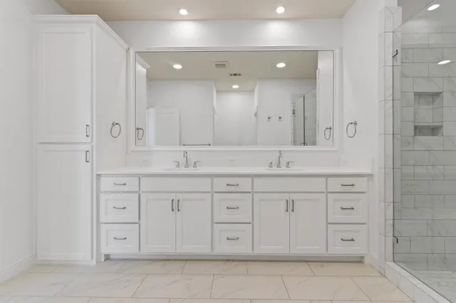 a bathroom with a granite countertop sink two mirror and shower