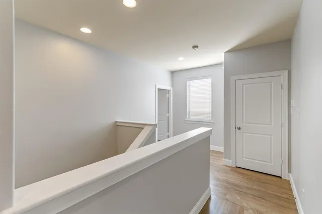 a view of a hallway with wooden floor and staircase