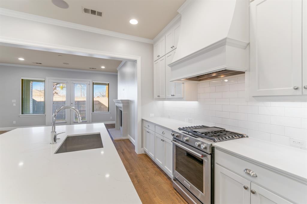 6531 Roper Street Dallas, TX 75209 - Photo 10 of 40 a kitchen with granite countertop a stove and white cabinets