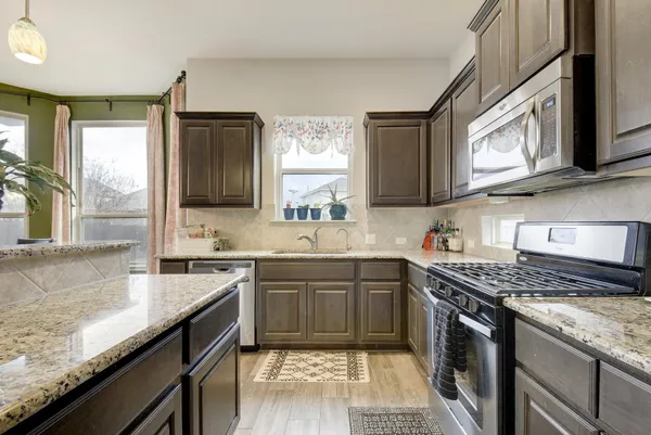 a kitchen with stainless steel appliances granite countertop a sink stove and cabinets