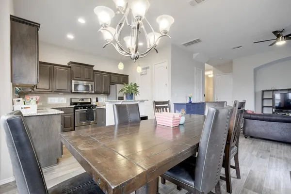 a view of a dining room and livingroom with furniture wooden floor a rug a fireplace and a chandelier
