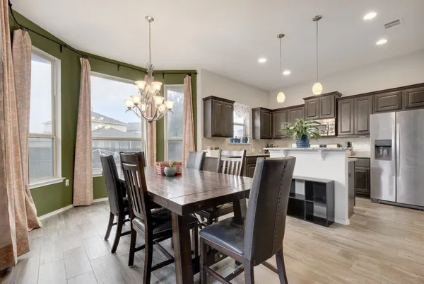 a dining room filled chandelier and wooden floor