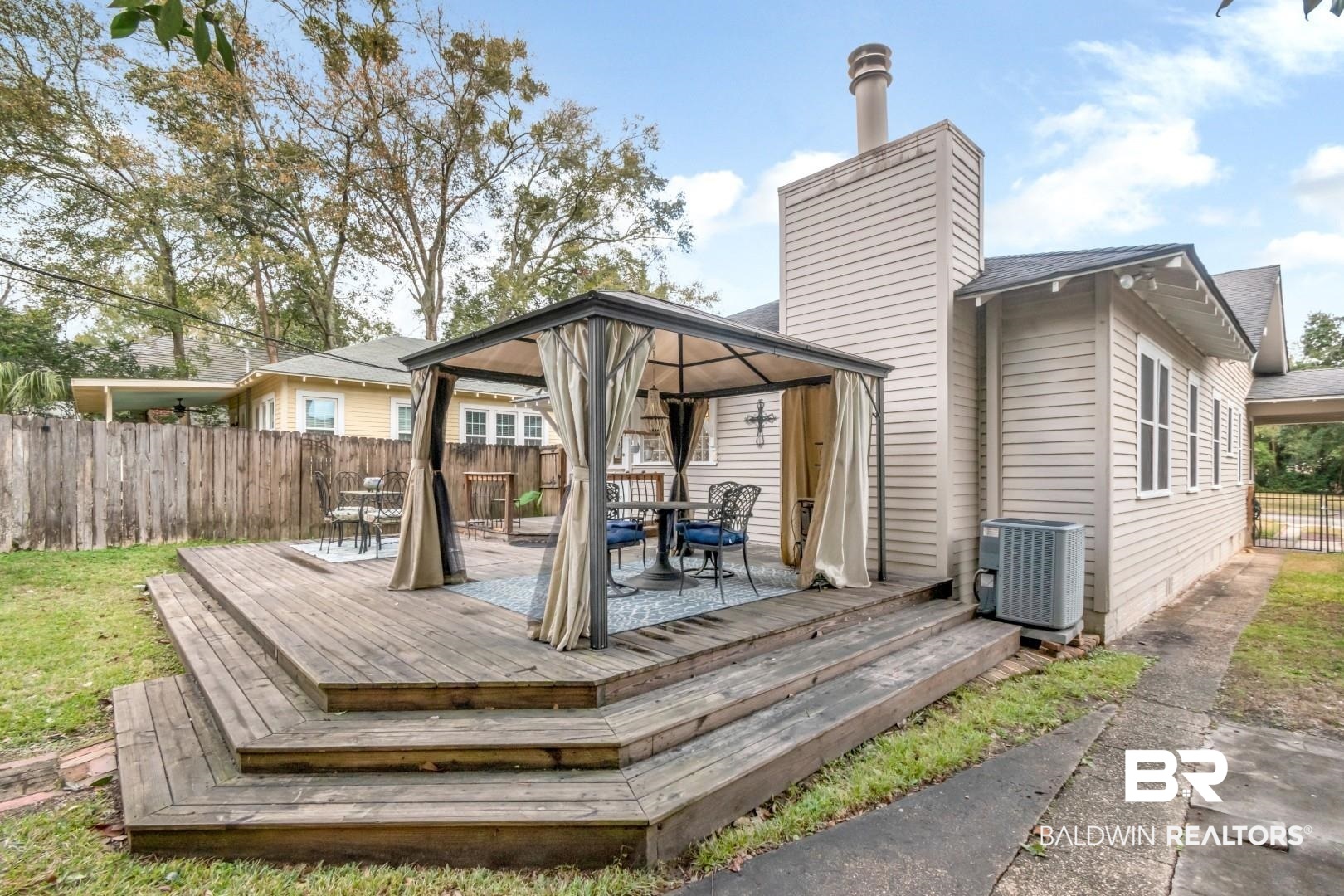 135 Silverwood Street Mobile, AL 36607 - Photo 29 of 32 Back of property featuring a gazebo, a wooden deck, outdoor dining area, and a chimney