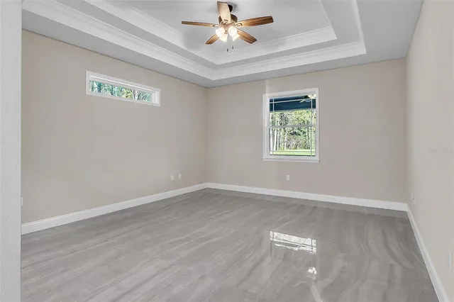 an empty room with wooden floor chandelier fan and windows