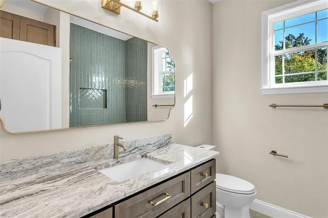 a bathroom with a granite countertop sink a toilet and a mirror