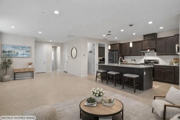 a kitchen with stainless steel appliances kitchen island granite countertop a refrigerator a stove top oven a sink a dining table and chairs