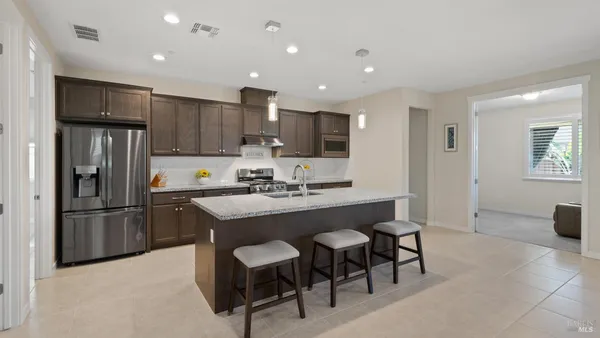 a kitchen with stainless steel appliances kitchen island granite countertop a sink and a refrigerator