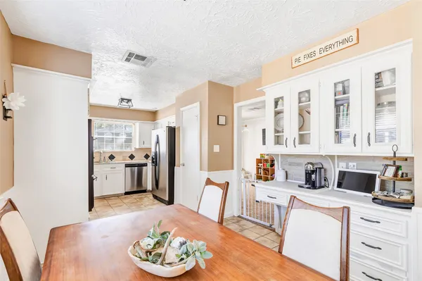 a living room with stainless steel appliances kitchen island granite countertop a refrigerator a stove and a dining table with wooden floor