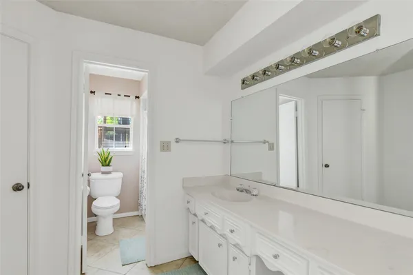 a bathroom with a granite countertop sink a toilet and a shower
