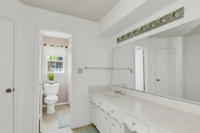 a bathroom with a granite countertop sink a toilet and a shower