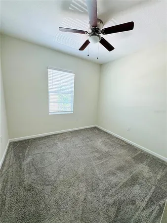 an empty room with a window and a fan