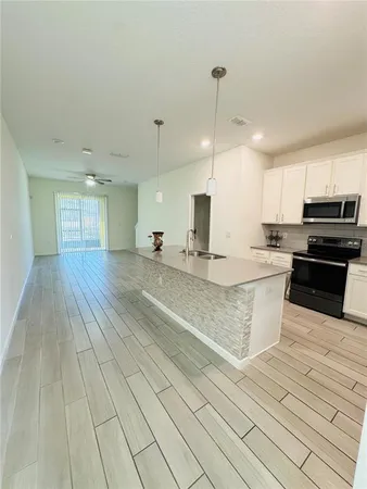 a large kitchen with kitchen island a sink dishwasher a stove a oven with white cabinets and wooden floor