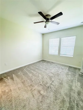 an empty room with a ceiling fan and window