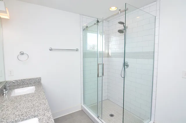 a bathroom with a granite countertop sink a shower and a mirror