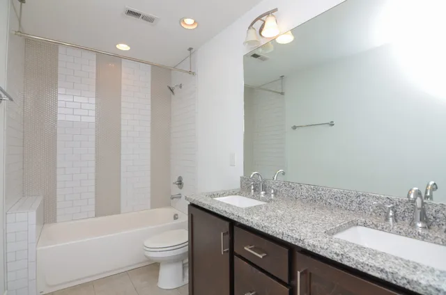 a bathroom with a granite countertop sink a toilet a shower and a mirror
