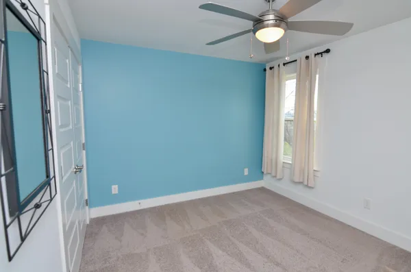 an empty room with a ceiling fan and window