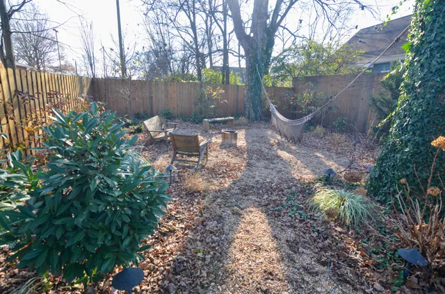 a view of a backyard with large tree and wooden fence