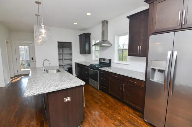 a kitchen with stainless steel appliances granite countertop a sink a stove and refrigerator