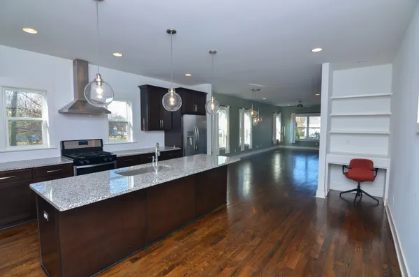 a kitchen with stainless steel appliances granite countertop a stove a sink and a wooden floors