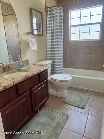 a bathroom with a granite countertop sink a toilet a mirror and bathtub