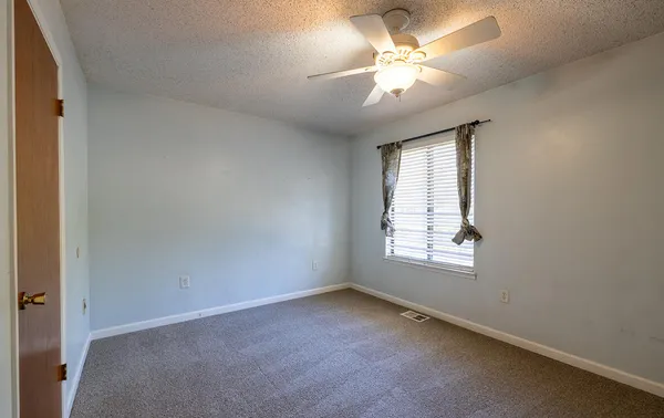 an empty room with windows and fan
