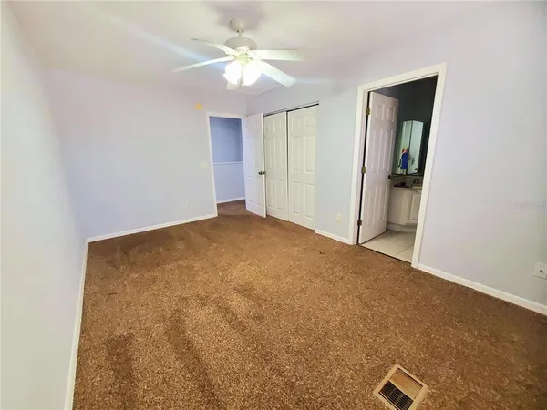 an empty room with windows and fan