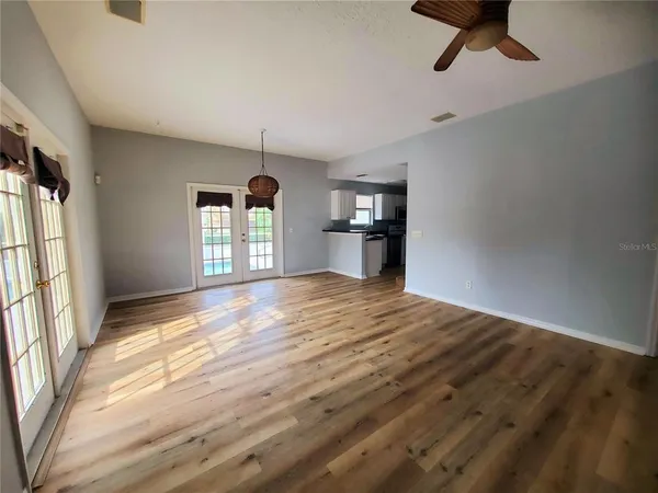 a view of empty room with wooden floor and fan