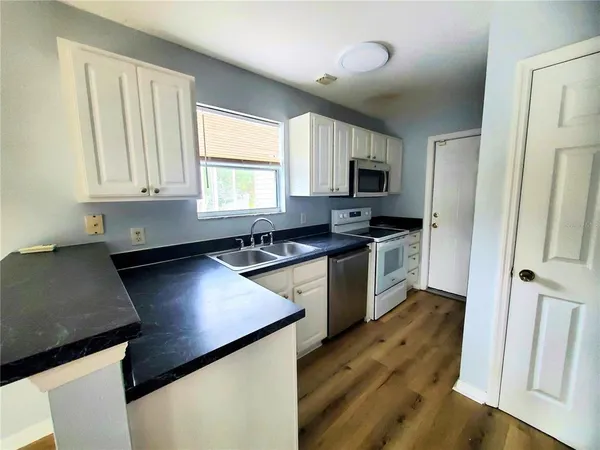a kitchen with granite countertop a sink cabinets and stainless steel appliances