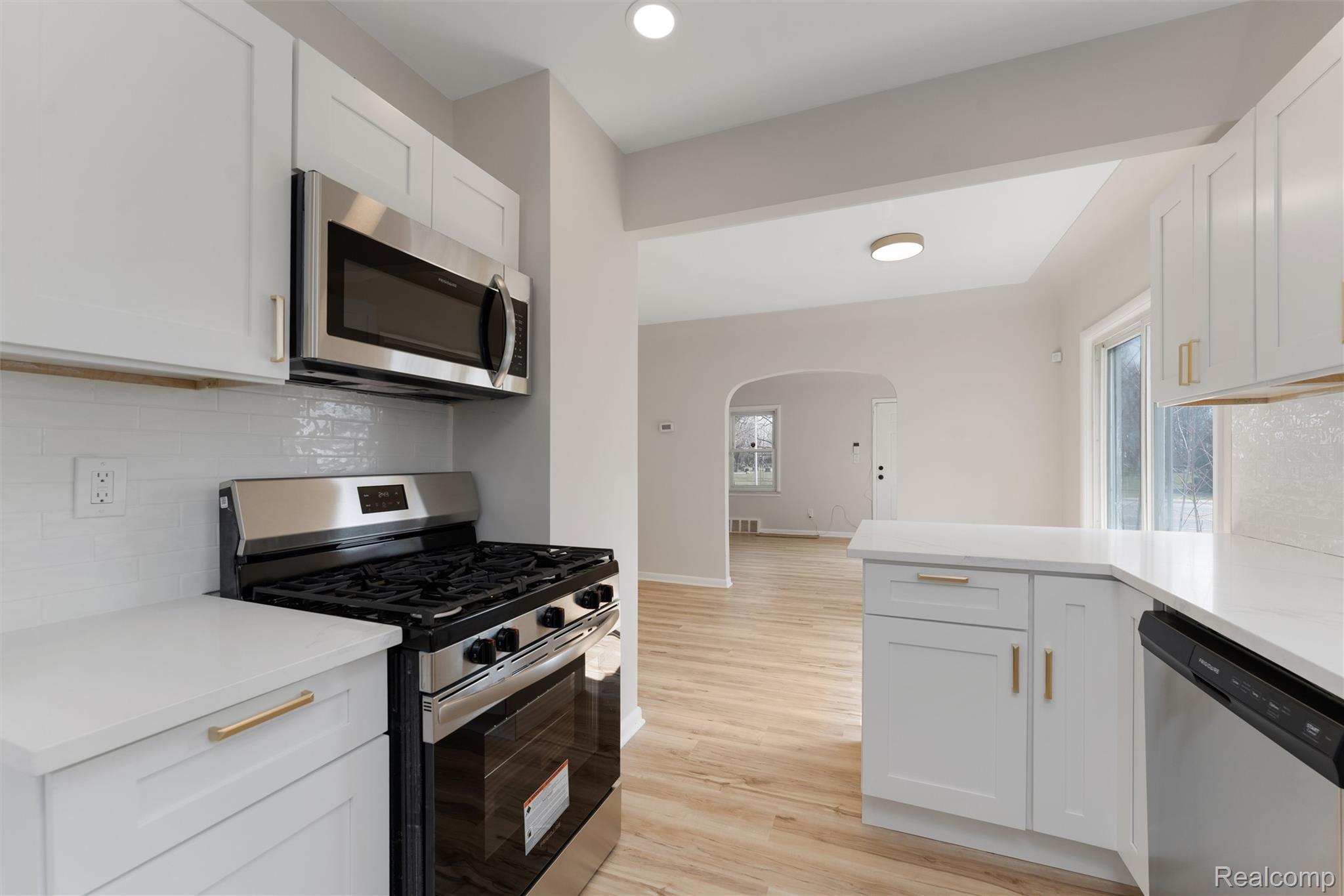 917 Perry Street Pontiac, MI 48340 - Photo 17 of 37 Kitchen featuring stainless steel appliances, backsplash, white cabinetry, arched walkways, and recessed lighting