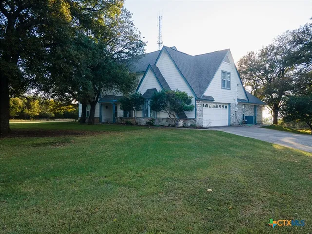 a view of a house next to a big yard and large trees