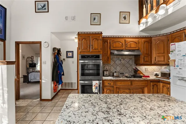 a kitchen with stainless steel appliances granite countertop a refrigerator and a stove